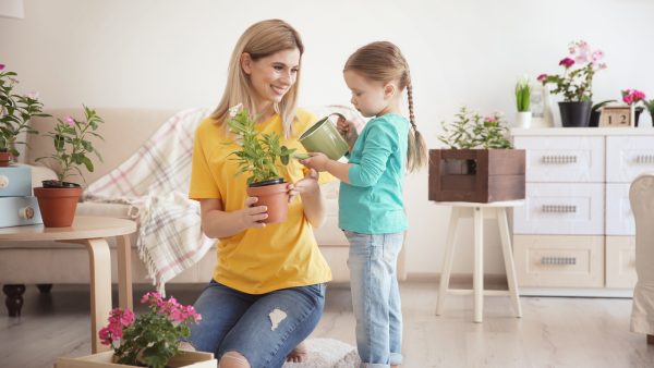 Mujer y niña regando planta y ahorrando agua